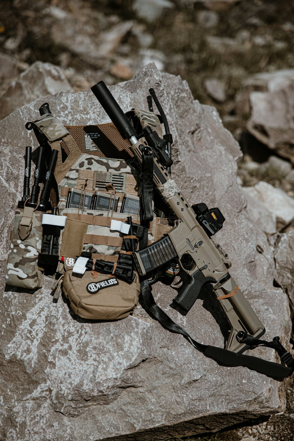 Tactical gear arranged on a grey rock outdoors.
