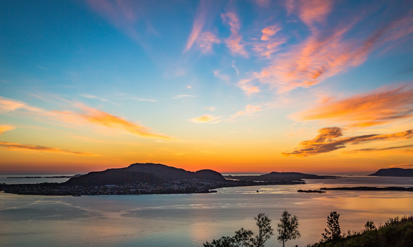 Coastal islands with small buildings sit under a sunset sky.